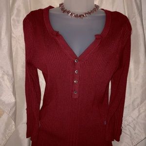 This is a brick-ish red sweater top with buttons that come down in the front.